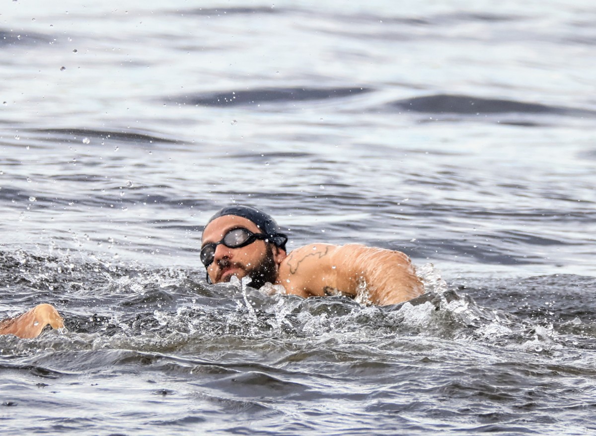 Chay Suede pratica natação no mar mesmo com tempo nublado no Rio